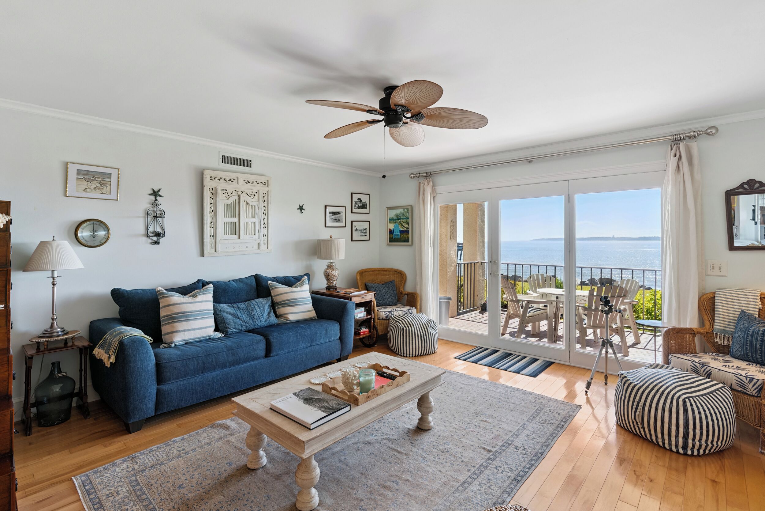 A spacious living room with a blue sofa, a wooden coffee table, and a balcony with outdoor furniture.