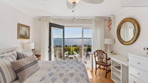 A bedroom with a bed, a desk, a chair, and a view of the sea. - Ocean Front Escape sleeps 4 (St Simons Island)