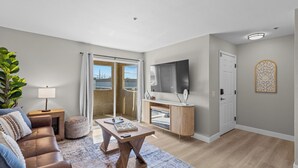 A modern living room with a sofa, coffee table, and a TV on a wooden cabinet. - Modern Las Vegas Condo Near Strip w/ Pool & Gym and free parking NO RESORT FEES (Paradise)