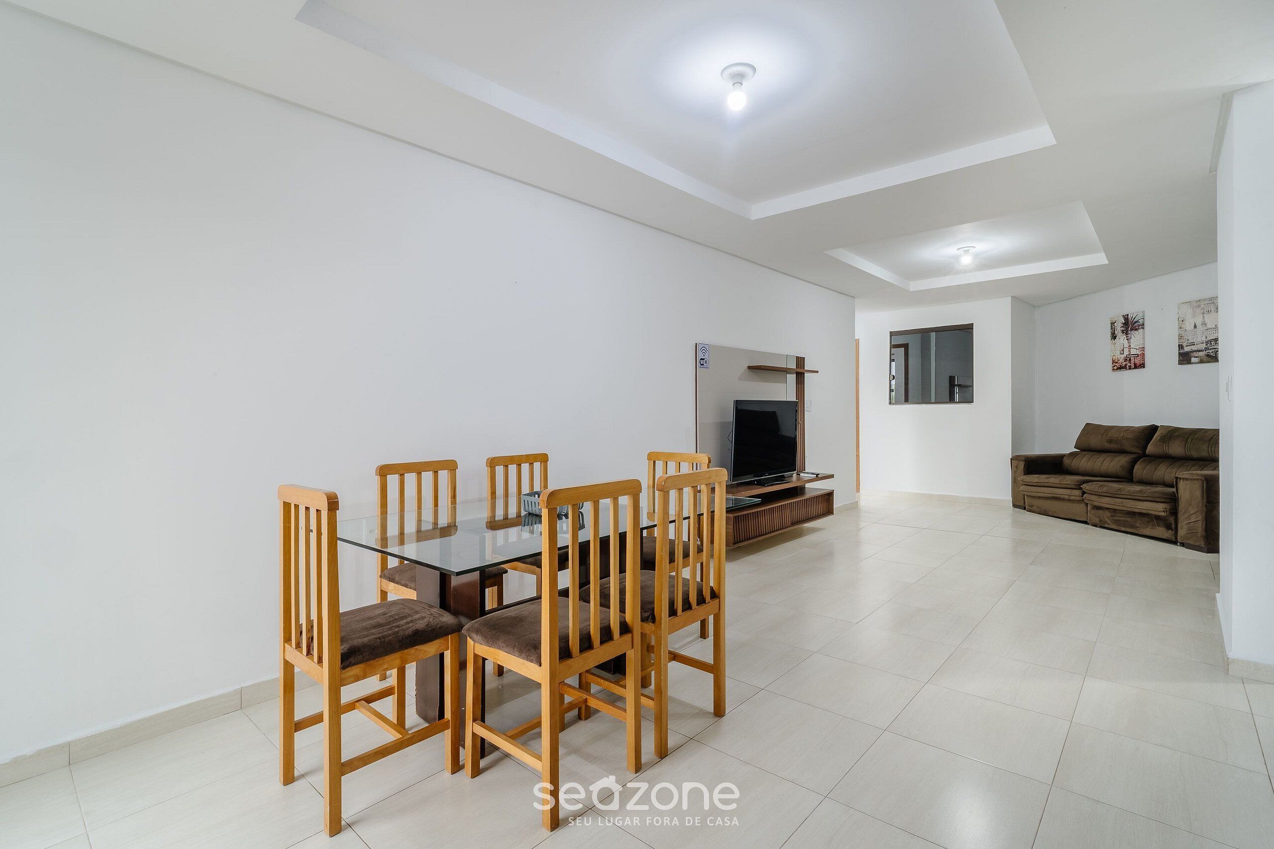 A modern living room with a dining area, a sofa, a TV, and a ceiling light.