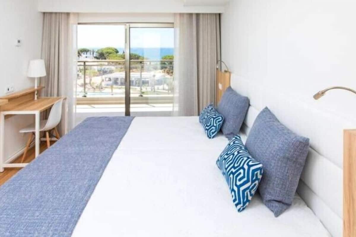 Una habitación de hotel con cama, escritorio, televisión y vistas al exterior.