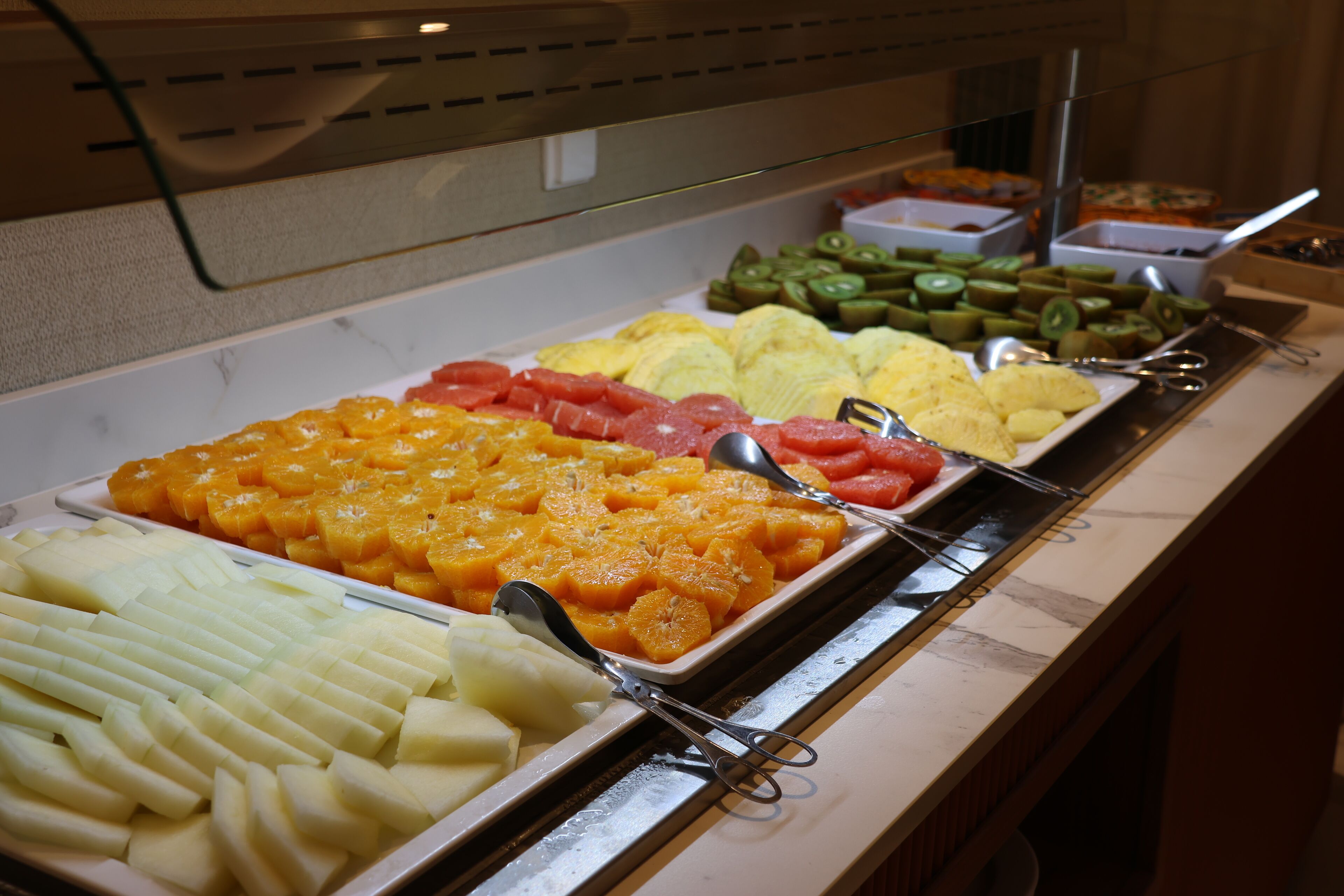A buffet with various fruits and vegetables arranged in trays.
