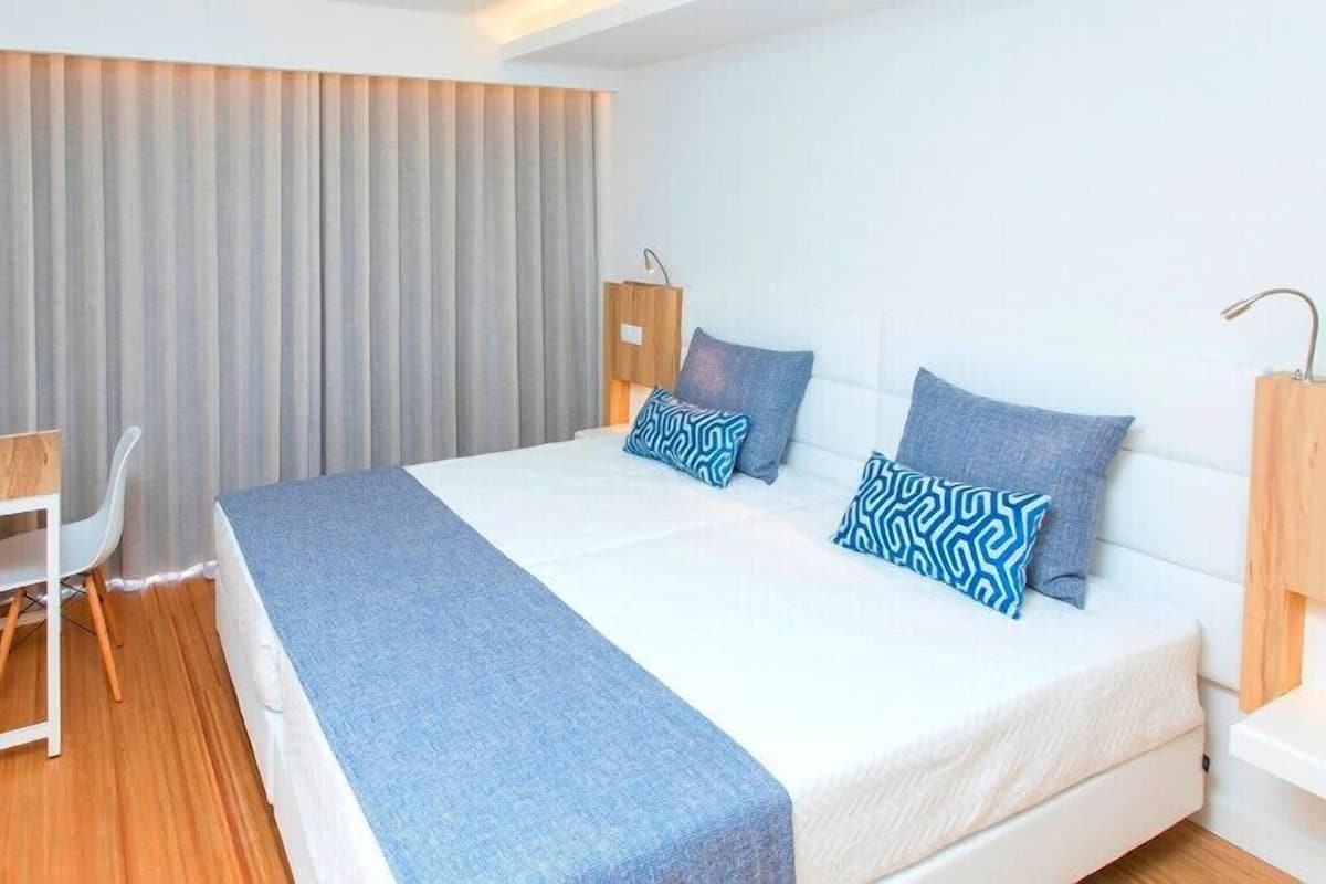Una habitación de hotel moderna con una cama grande, un escritorio y una silla.