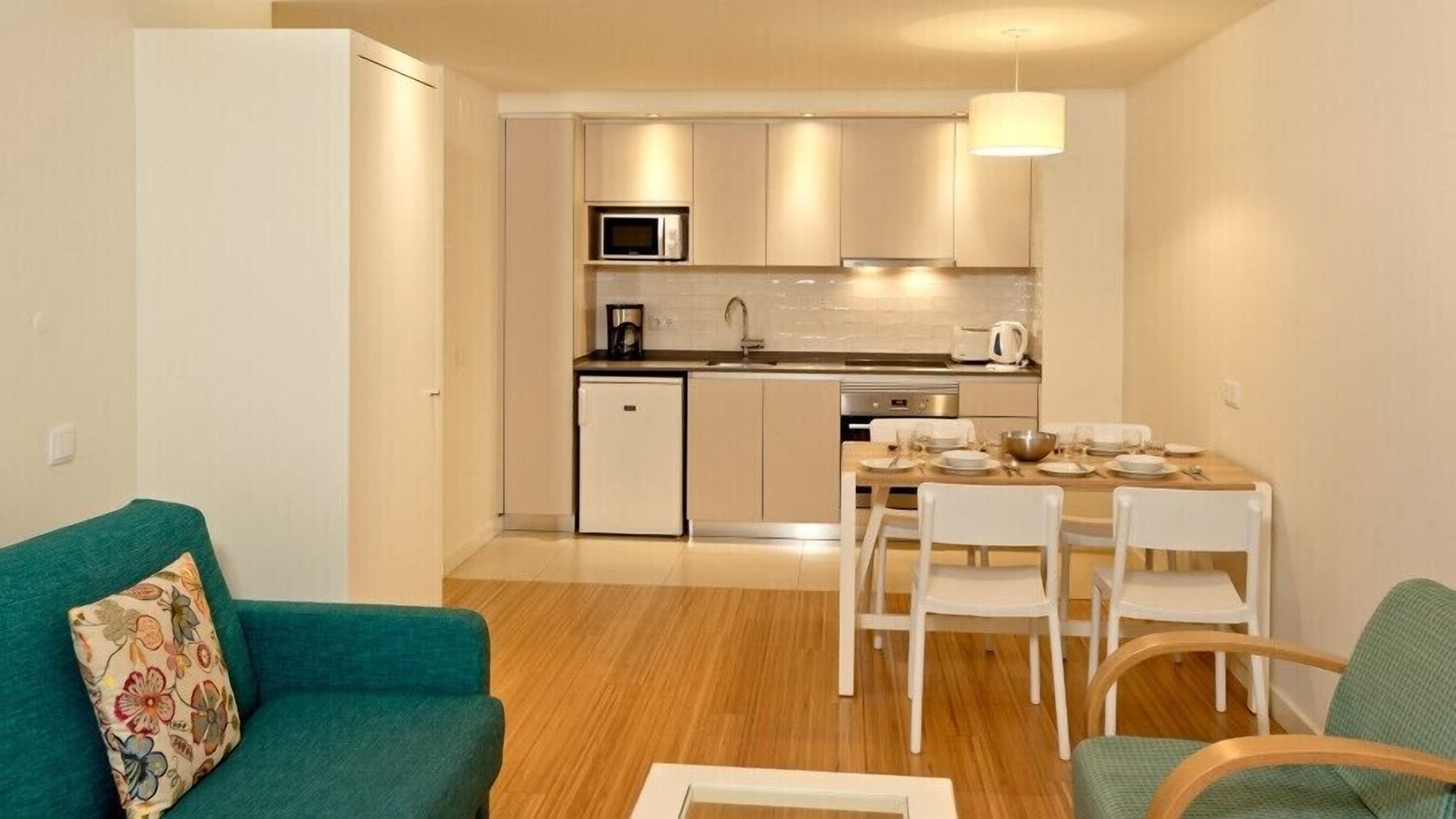 A compact kitchen with a microwave, stove, and dining area with chairs and a table set for a meal.
