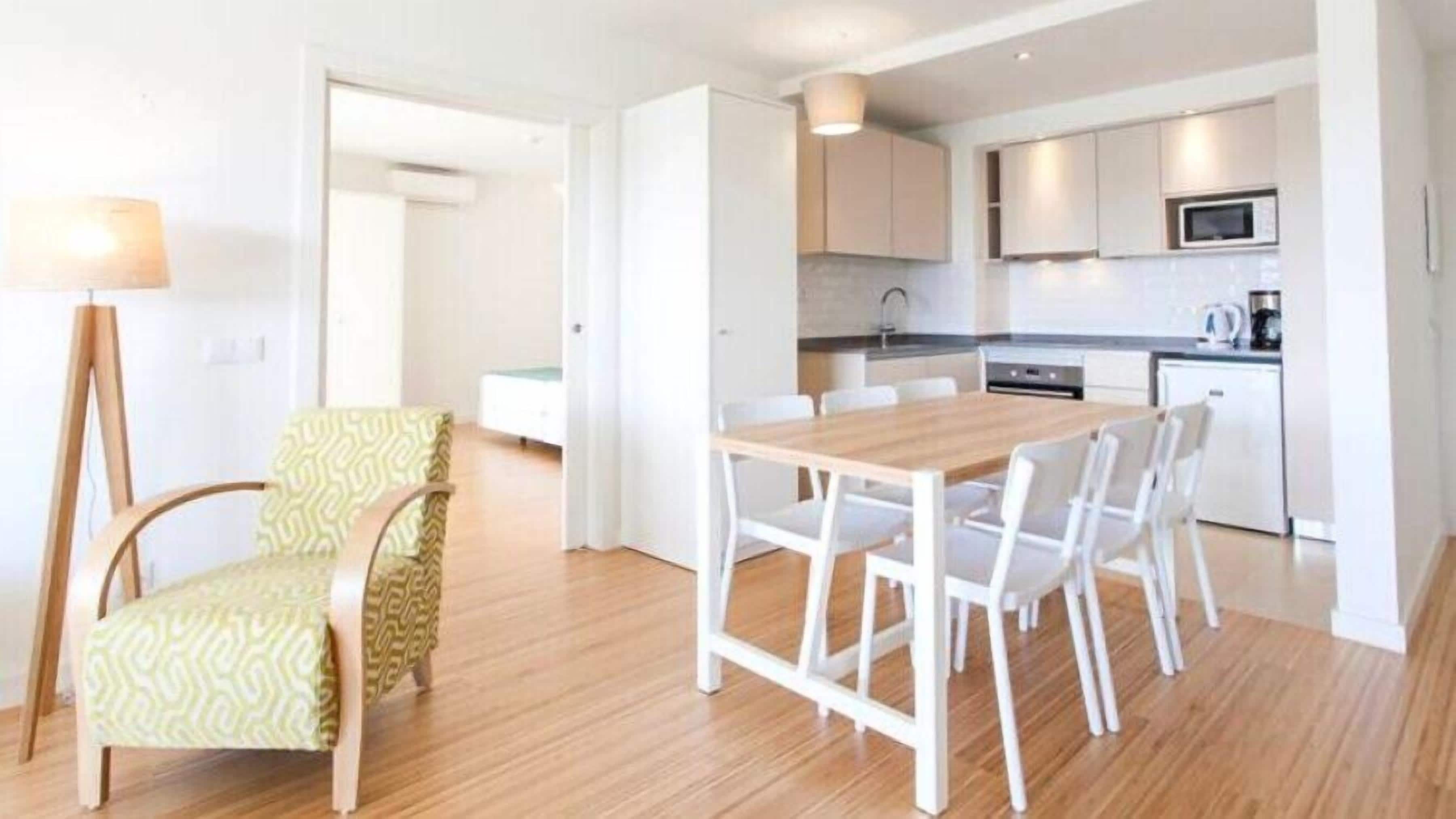 Una cocina moderna con armarios blancos, una mesa de comedor de madera y un microondas.