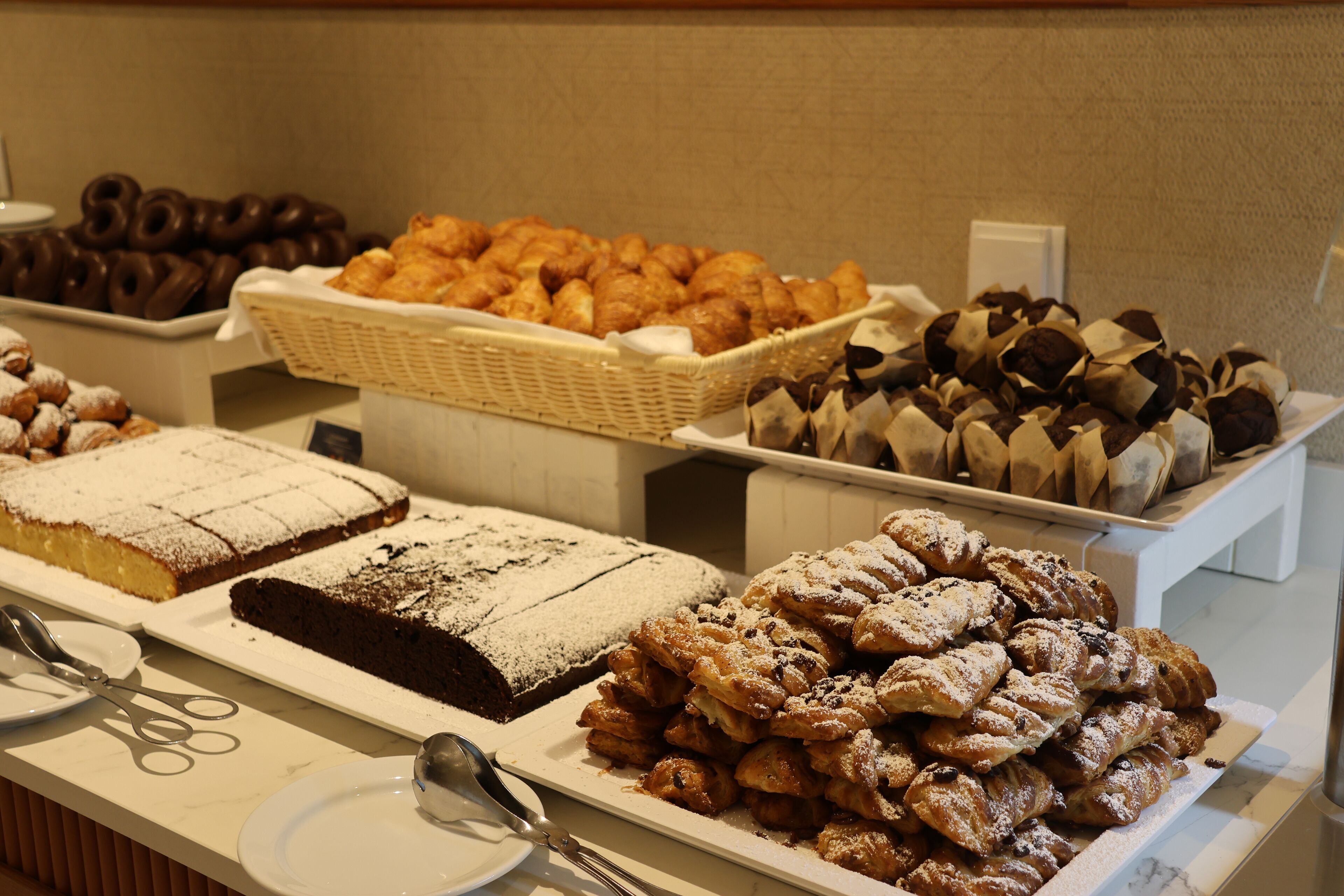 Un buffet proposant une variété de pâtisseries et de desserts, notamment des gâteaux et des viennoiseries.