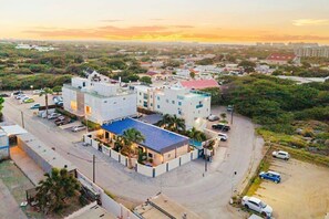 Ein mehrstöckiges Hotel mit Innenhof, Parkplatz und umliegender Bepflanzung.