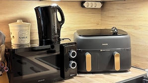 A kitchen with white cabinets, a black 3D wave microwave, a Philips toaster, and a garlic container.