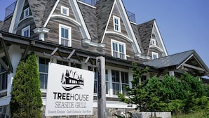 Een groot, twee verdiepingen hoog gebouw met een bord voor Treehouse Seaside Grill, met een nautisch logo.