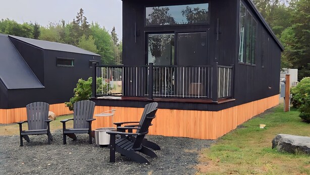 Een modern huis met twee verdiepingen, een terras, buitenmeubels en een groot raam.