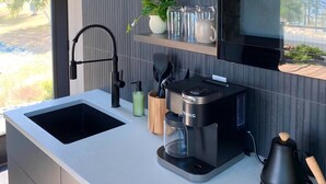 Een moderne keuken met een inbouwgootsteen, een koffiezetapparaat en een waterkoker op het aanrecht.