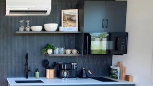 Een moderne keuken met grijze kastjes, een ingebouwde magnetron en een koffiezetapparaat.