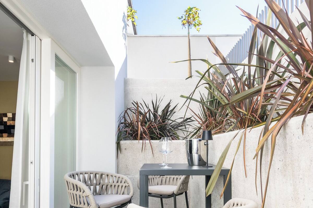Eine Terrasse im Freien mit zwei Korbstühlen, einem Tisch und einem Blumentopf.