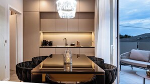 Una cocina moderna con una araña, una mesa de comedor con sillas y vistas al exterior.