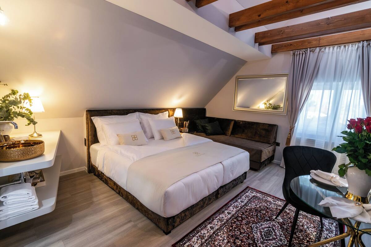 Ein Schlafzimmer mit Bett, Nachttisch, Stuhl und einem kleinen Tisch mit Blumenvase.
