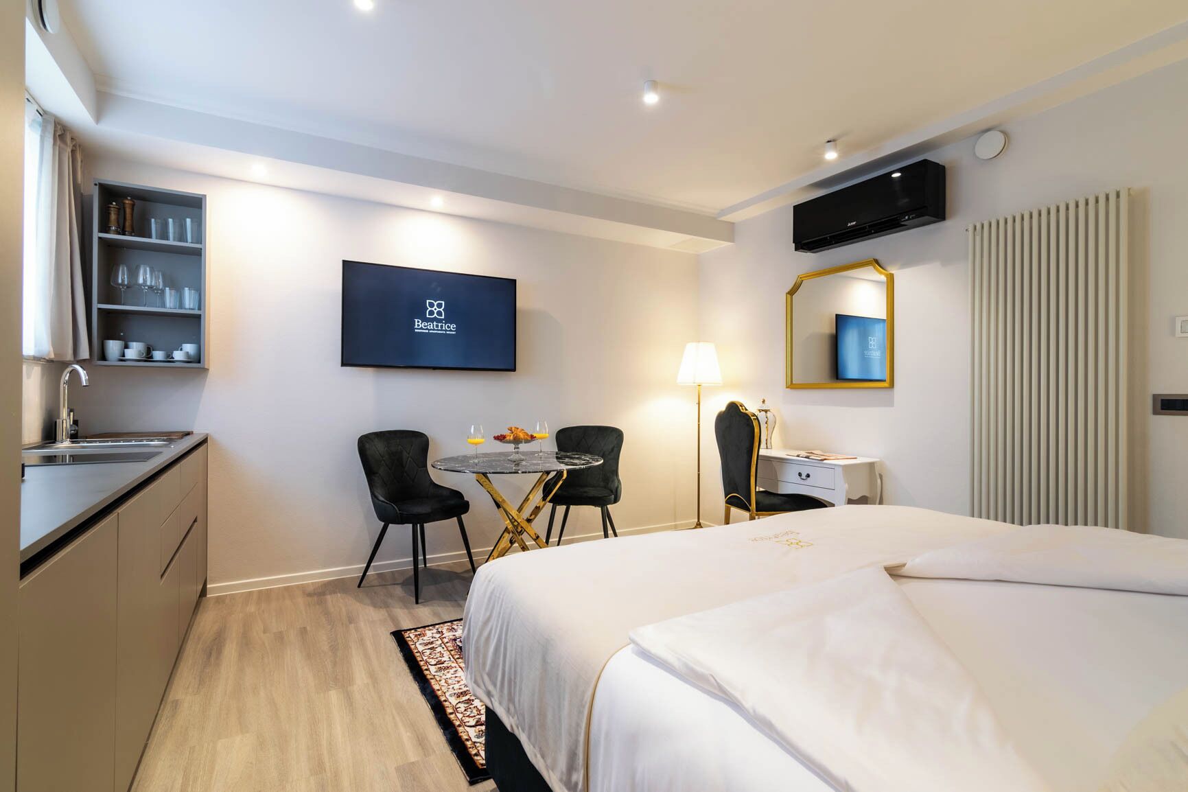 Habitación de hotel con cama, escritorio, sillas, televisor y minibar.