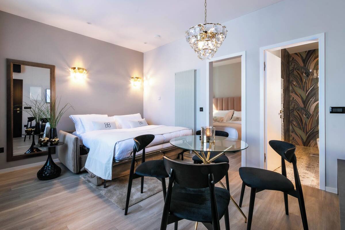 Ein modernes Schlafzimmer mit Bett, Nachttischen, einem Glastisch und Stühlen.