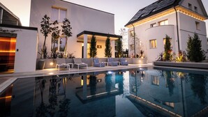 Un área de piscina moderna con sillones de descanso y una piscina cristalina.