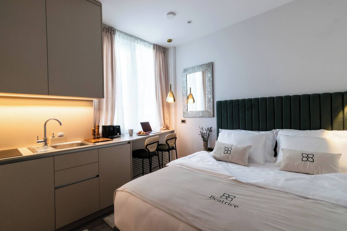 Ein Hotelzimmer mit Bett, Schreibtisch, Laptop, Waschbecken und Spiegel.