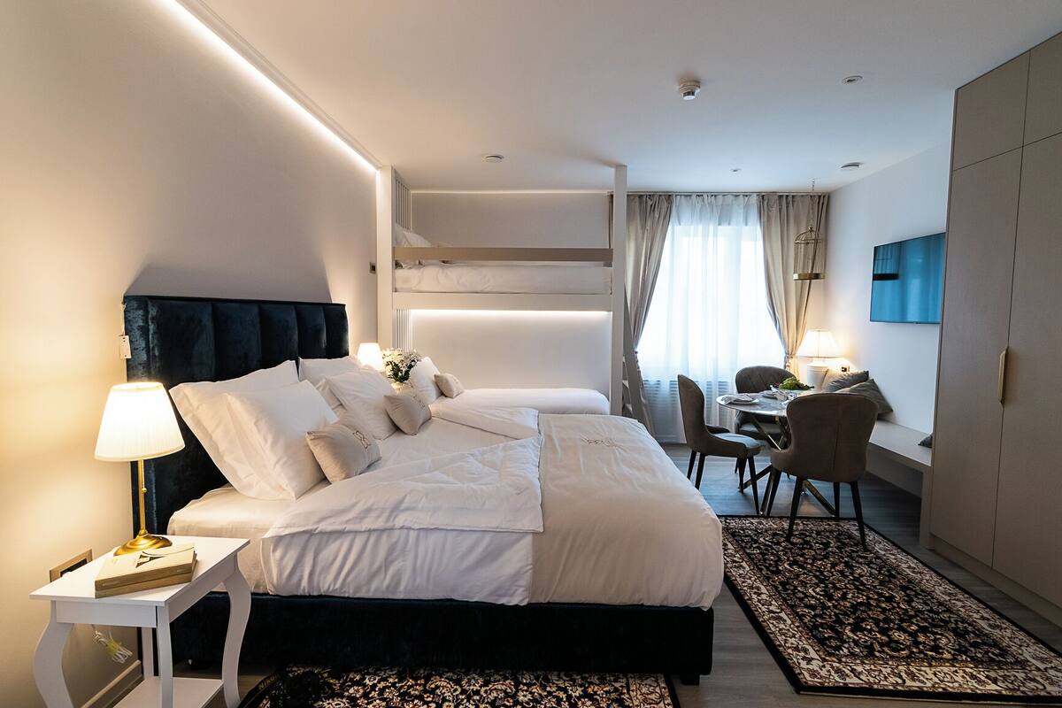 Ein modernes Hotelzimmer mit einem großen Bett, Nachttischen, einem Schreibtisch und einem Sessel.