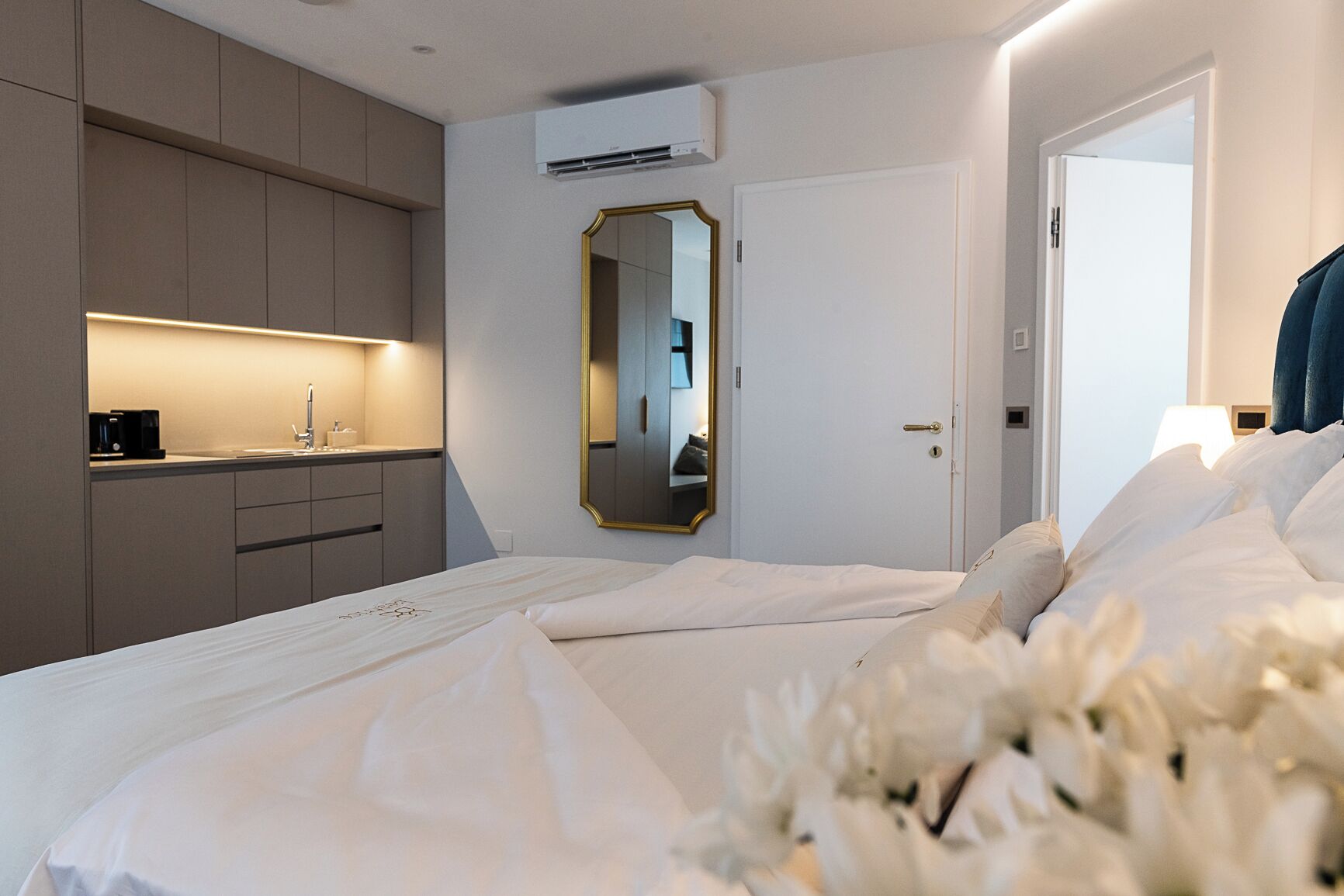 Ein Hotelzimmer mit Bett, Nachttisch, Spiegel, Kleiderschrank und Klimaanlage.