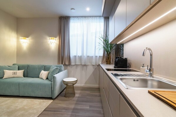 A modern kitchen with a built-in sink, a green sofa, and a small round table.