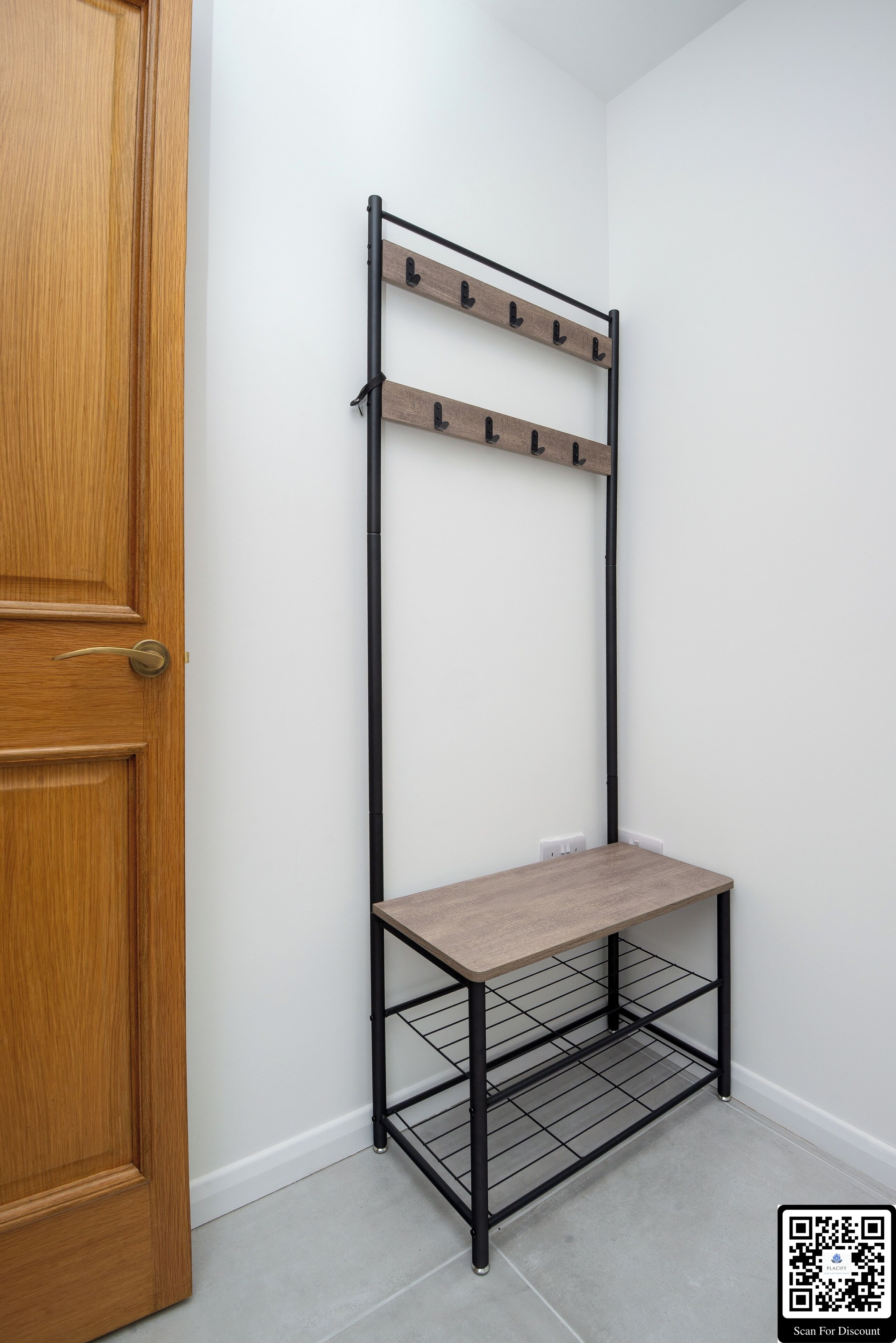 Un coin avec une porte en bois, un présentoir en métal noir doté d’étagères et un mur blanc.