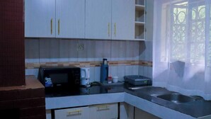 Una cucina compatta con mobili bianchi, un forno a microonde, una macchina da caffè e un lavello.