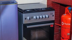 Una cucina con piano cottura, forno e una bombola di gas rossa.