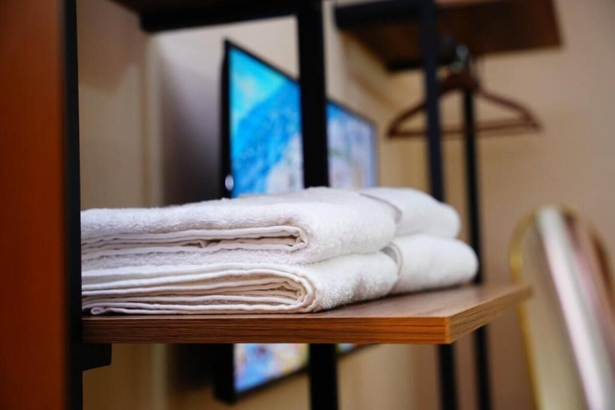 Un mucchio di asciugamani bianchi su uno scaffale di legno in una camera d'albergo.