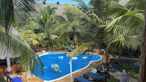 A swimming pool surrounded by palm trees and lounge chairs. - Oasis Nungwi (Nungwi)