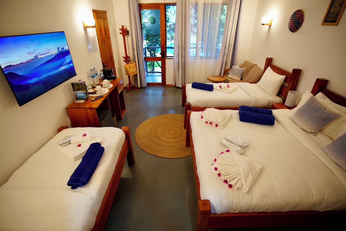 Habitación de hotel con dos camas, televisor, escritorio con silla y vistas al exterior.
