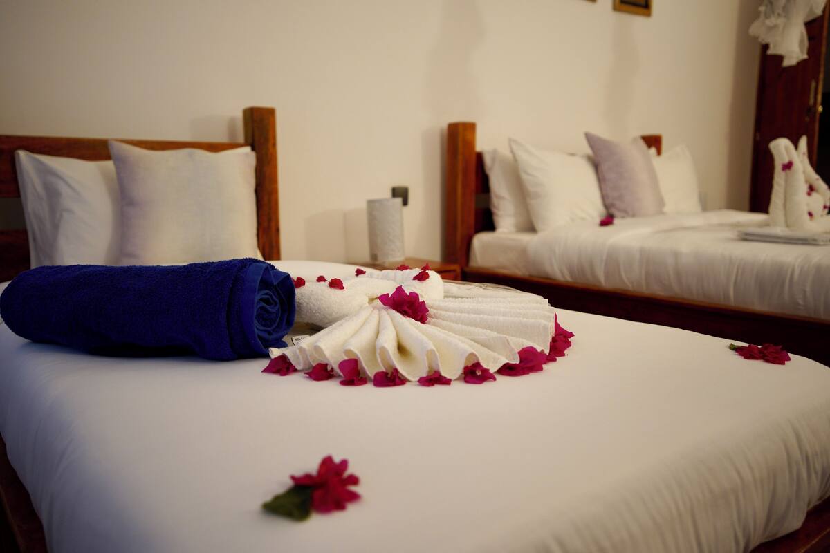 Habitación de hotel con dos camas, ropa blanca y una toalla azul sobre una de ellas.