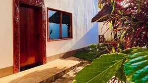 A two-story building with a red door, a balcony, and a thatched roof. - Oasis Nungwi (Nungwi)