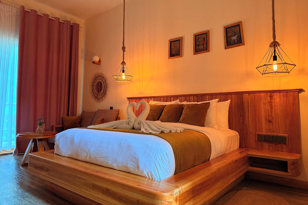 Um quarto espaçoso com cama de madeira, mesa de cabeceira, luminária fixada na parede e um criado-mudo.
