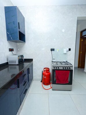 Une cuisine équipée d’une cuisinière à gaz, d’un four à micro-ondes et d’une bouteille de gaz.