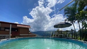 A swimming pool with a view of mountains, a covered seating area, and a building with a red roof. - FARM WITH BEAUTIFUL VIEW 40MIN FROM MEDELLÍN. SPORTS COURT, SWIMMING POOL AND GYM. (Barbosa)