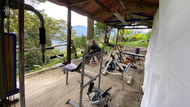 An outdoor gym with exercise equipment, a covered area, and a view of a lake and mountains. - FARM WITH BEAUTIFUL VIEW 40MIN FROM MEDELLÍN. SPORTS COURT, SWIMMING POOL AND GYM. (Barbosa)