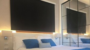 Una habitación de hotel moderna con una cama grande, mesitas de noche y un espejo amplio.