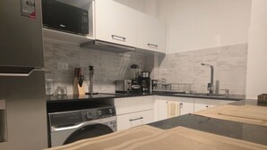 Una cocina moderna con electrodomésticos de acero inoxidable, armarios blancos y encimera negra.