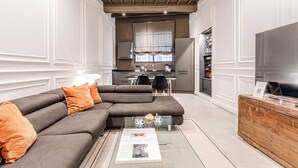 Un salon moderne avec un canapé d’angle, une table basse en verre et une commode en bois.