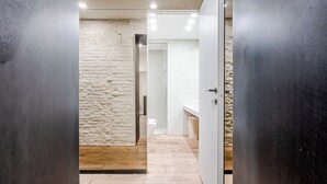 Une salle de bain moderne avec un mur en pierre, un plancher en bois et un lavabo blanc.