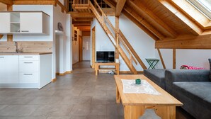 Une pièce de style loft avec un escalier en bois, une table à manger, un canapé et un coin cuisine.