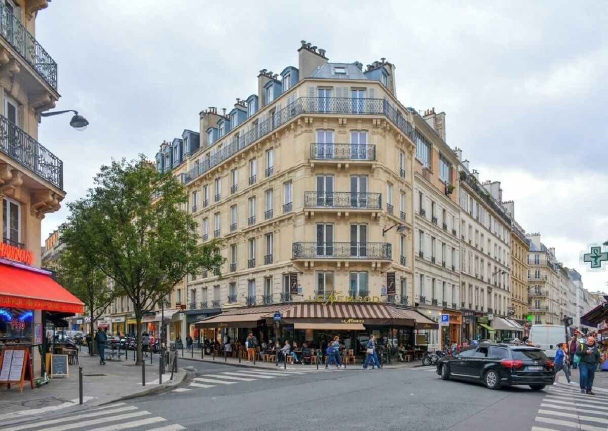Um edifício de vários andares com arquitetura europeia clássica, com varandas e um café no andar térreo.