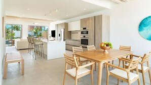 Een moderne keuken met houten kastjes, een centraal eiland en een eethoek met houten stoelen.