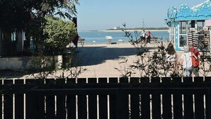 A beach view with a clear sky, a few people, and a building with a blue roof. - Atelier Marin (La Rochelle)