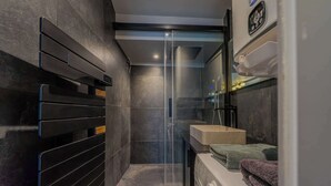 Ein modernes Badezimmer mit Duschabtrennung aus Glas, integriertem Waschbecken und Waschmaschine.