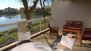 A terrace with a table and chairs, a wooden bench, and a view of a lake. - Apartment - The Gentle Tides (La Rochelle)