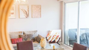 Ein Essbereich mit einem Tisch für vier Personen, einer Couch mit floralen Kissen und einem großen Fenster mit Blick.