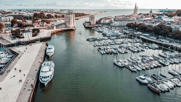 A marina with several boats docked, a prominent tower, and a historic building in the background. - Golden Waves Aparthotel - Kiwi Residence (Aytré)